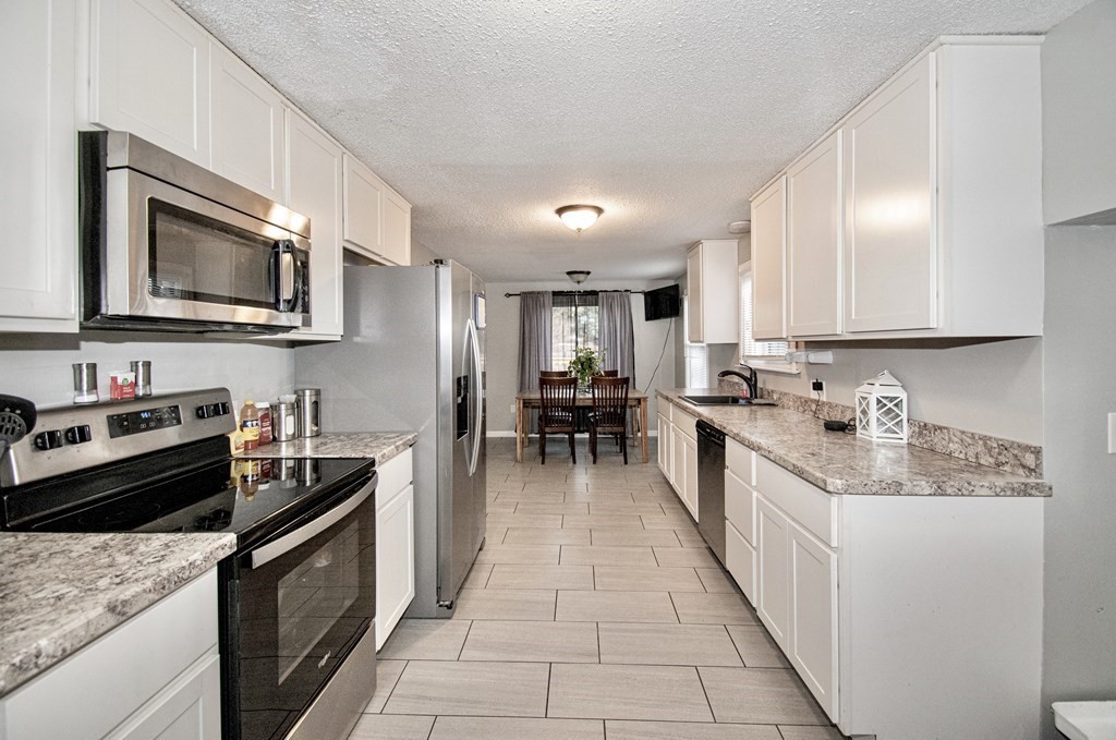 1617 Plumtree Road Springfield, MA 01119 - Photo 3 of 25 a kitchen with stainless steel appliances granite countertop a stove top oven a sink dishwasher a microwave oven and a dining table with wooden cabinet
