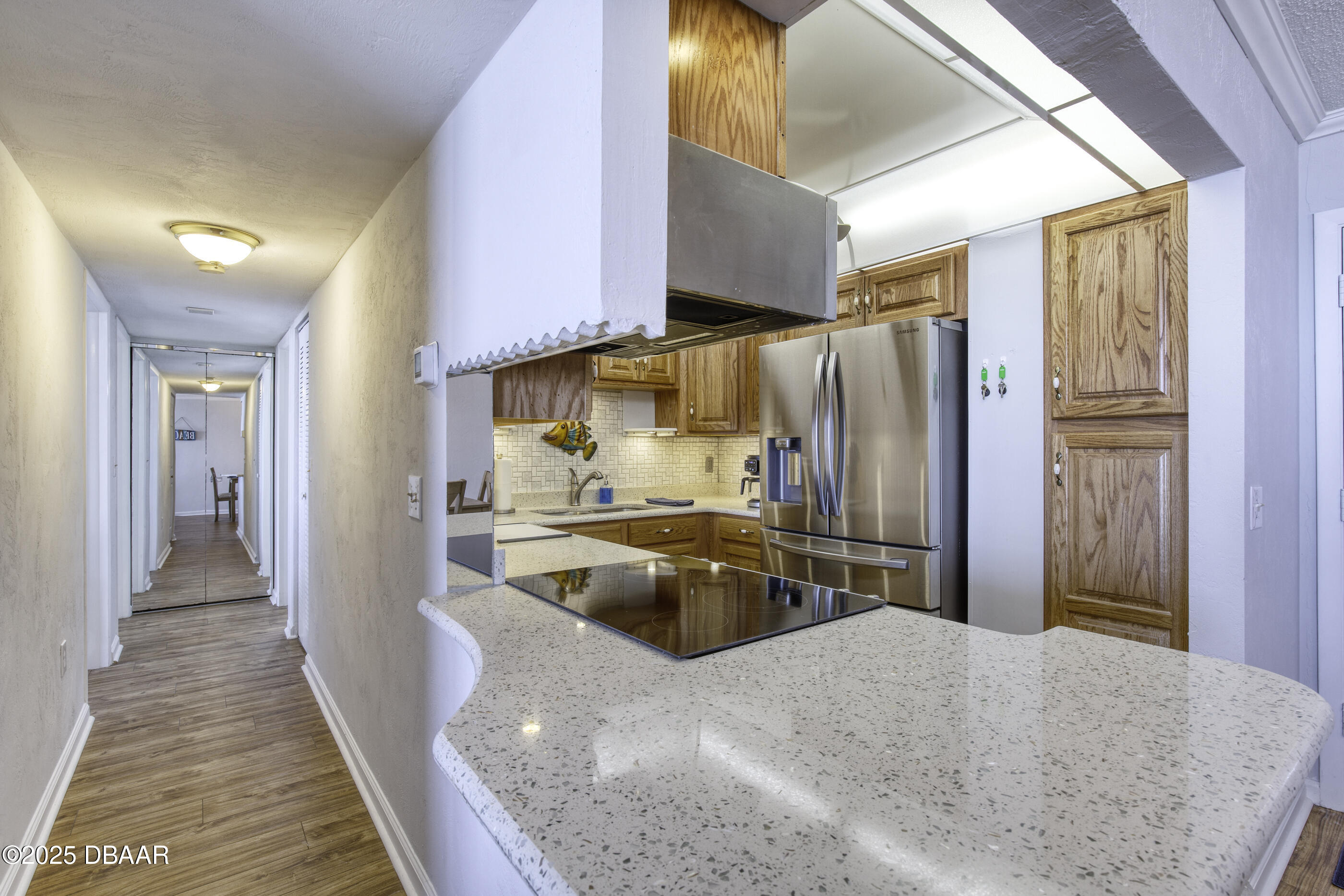 1415 Ocean Shore Boulevard, Unit 1010 Ormond Beach, FL 32176 - Photo 15 of 52 a kitchen with stainless steel appliances granite countertop a refrigerator a stove and a sink with wooden floor