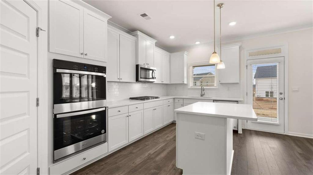 1912 Endress Circle Hampton, GA 30228 - Photo 12 of 43 a kitchen with stainless steel appliances granite countertop a stove a sink and white cabinets with wooden floors