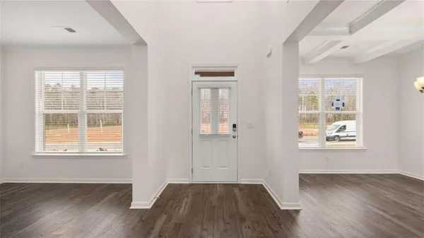 an empty room with wooden floor and windows