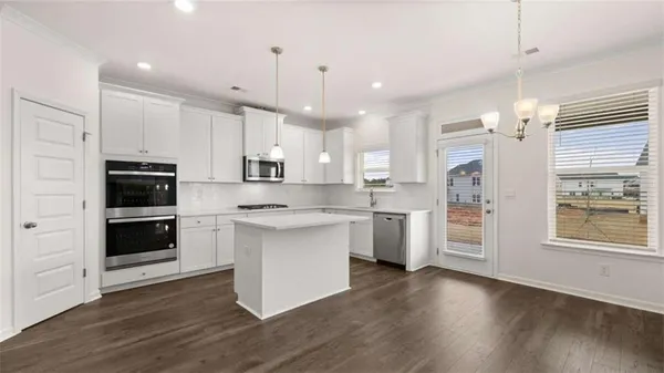 a kitchen with stainless steel appliances white cabinets a sink a stove a refrigerator and white cabinets