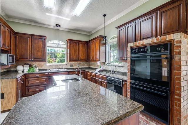 a kitchen with kitchen island granite countertop wooden cabinets a stove a sink and a window
