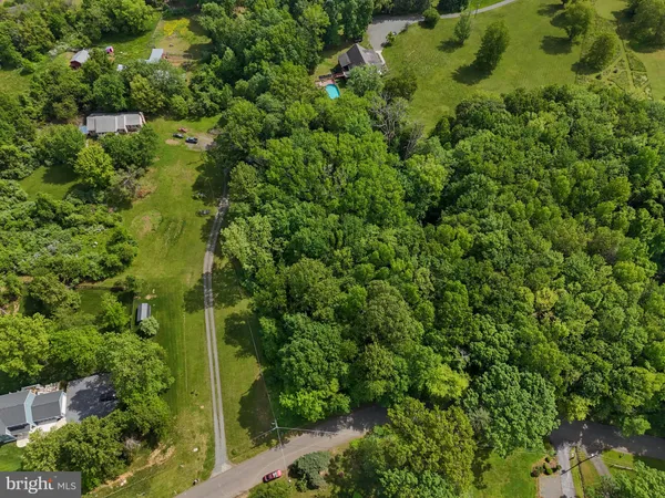 an aerial view of residential house with outdoor space and trees all around