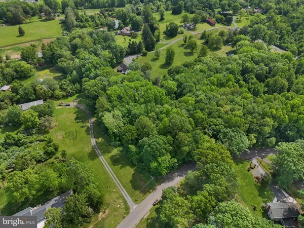 an aerial view of residential house with outdoor space and trees all around