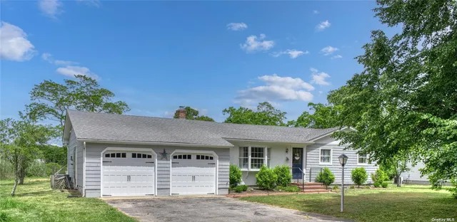 a view of a white house next to a yard with big trees