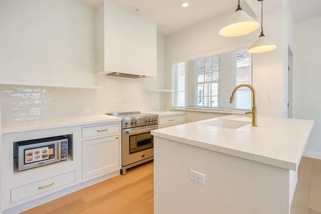a kitchen with granite countertop a stove a sink and a microwave