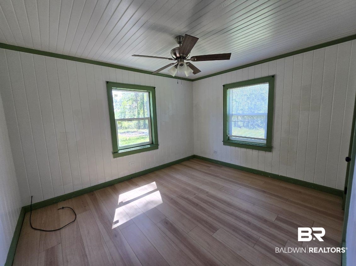 6464 Ridge Road Brewton, AL 36426 - Photo 13 of 14 Empty room with wooden walls, light wood-style floors, and a ceiling fan