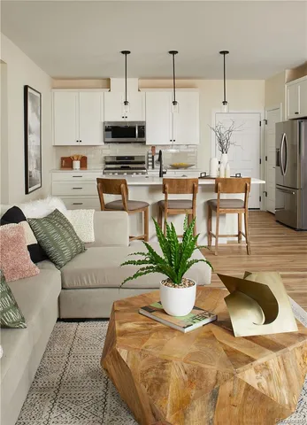 a living room with stainless steel appliances kitchen island granite countertop furniture a microwave a sink and white cabinets