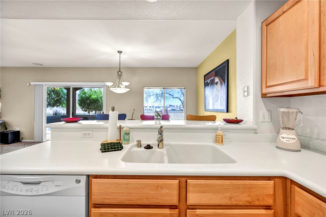 10730 Amber Ridge Drive, Unit 101 Las Vegas, NV 89144 - Photo 14 of 32 A well-lit kitchen with natural light, a white counter, and wood cabinetry for all your culinary needs.