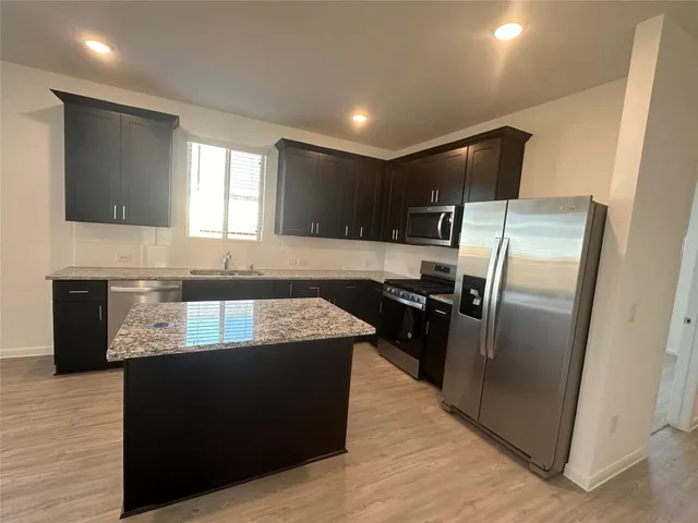 a large kitchen with granite countertop a refrigerator and a stove top oven