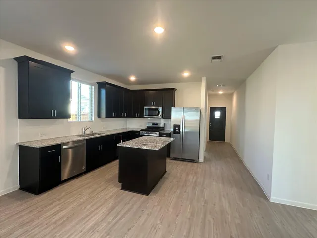 a large kitchen with stainless steel appliances granite countertop a large counter top and wooden floors