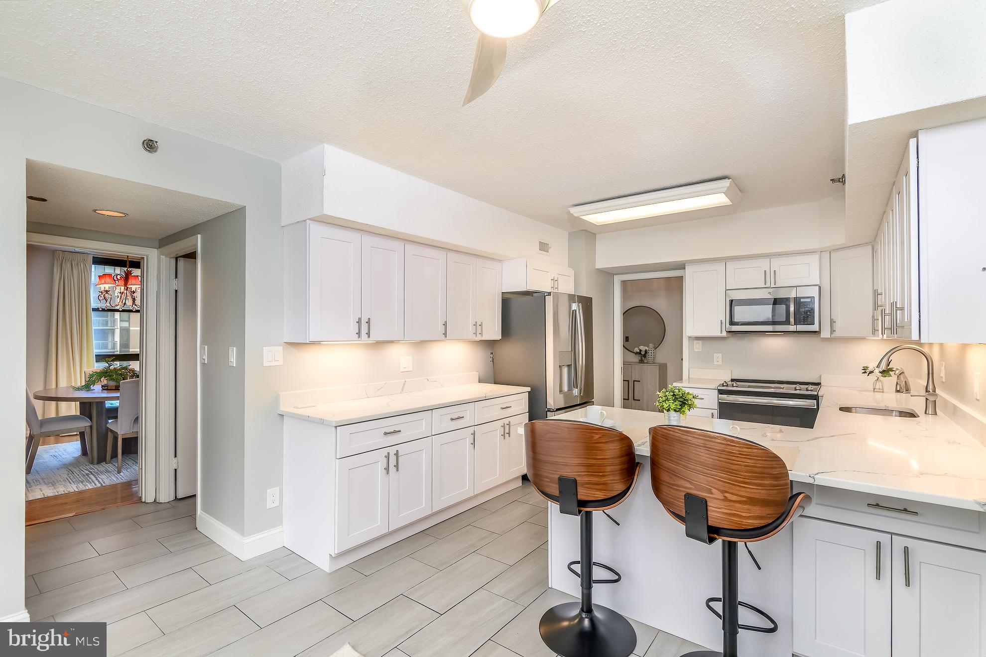 1016 South Wayne Street, Unit 604 Arlington, VA 22204 - Photo 15 of 42 a kitchen with stainless steel appliances kitchen island granite countertop a table chair and a refrigerator