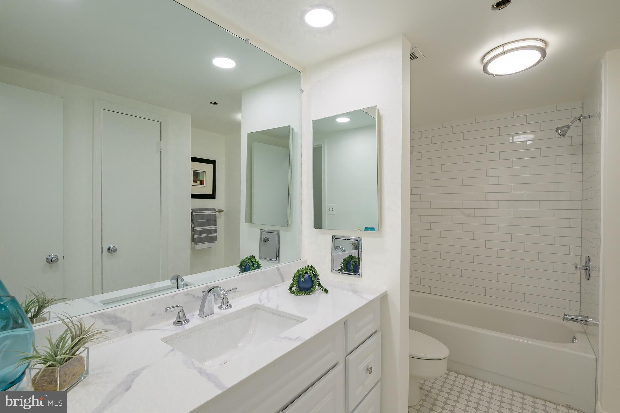1016 South Wayne Street, Unit 604 Arlington, VA 22204 - Photo 28 of 42 a bathroom with a sink double vanity granite tub shower and a mirror