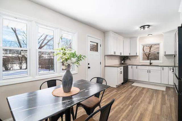 a kitchen with stainless steel appliances granite countertop a dining table chairs a granite counter tops and a window