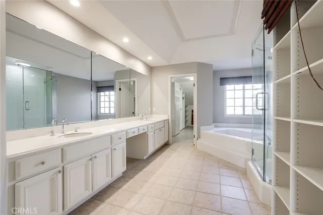 a large white bathroom with a large mirror vanity and a bathtub