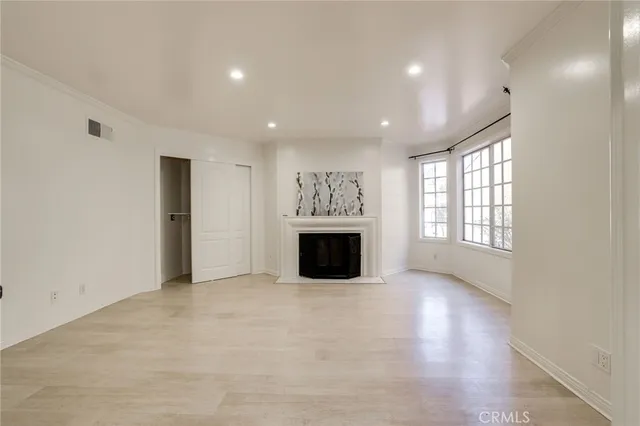 an empty room with windows and fireplace