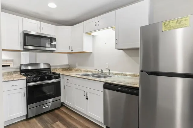 a kitchen with stainless steel appliances a refrigerator stove and white cabinets