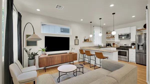 a living room with furniture a flat screen tv and kitchen view