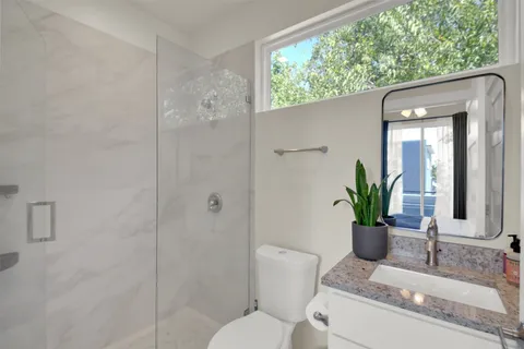 a bathroom with a granite countertop sink a toilet and shower