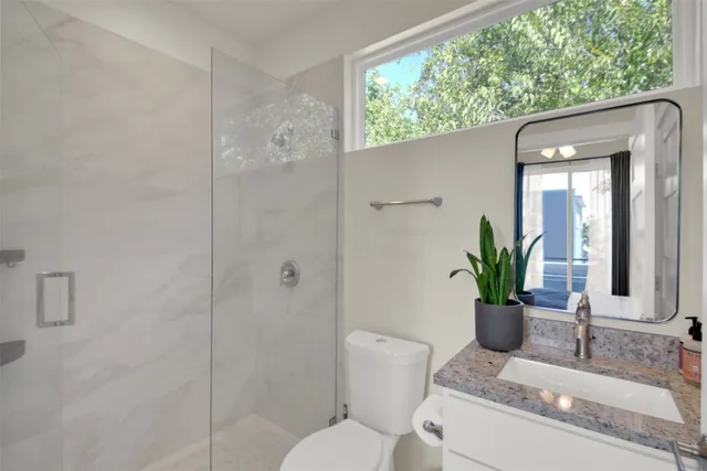 a bathroom with a granite countertop sink a toilet and shower