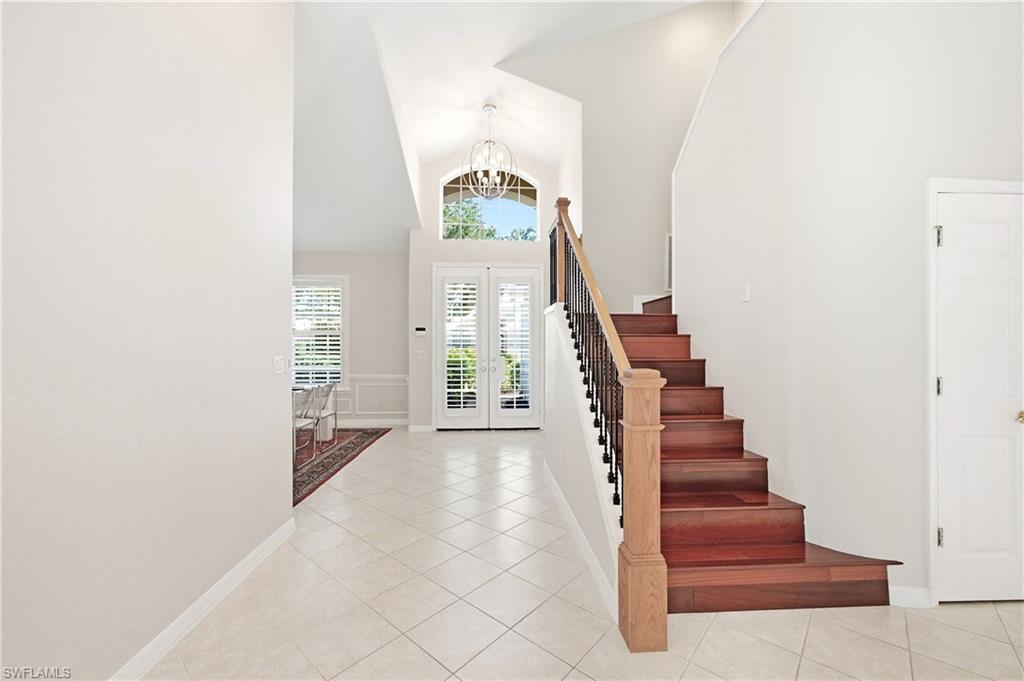 1960 Timarron Way Naples, FL 34109 - Photo 10 of 45 Entryway featuring a grand staircase with wood treads and a wrought iron baluster