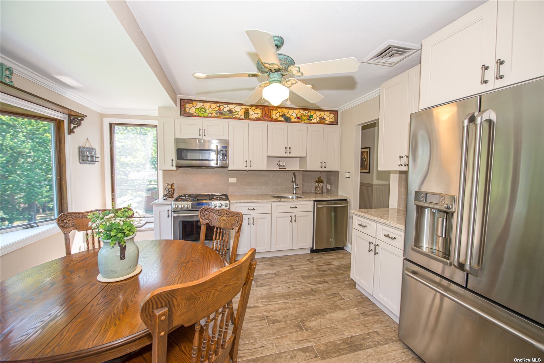 a kitchen with white cabinets stainless steel appliances and a dining table