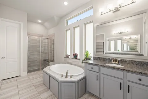 a bathroom with a granite countertop bathtub a sink and a window