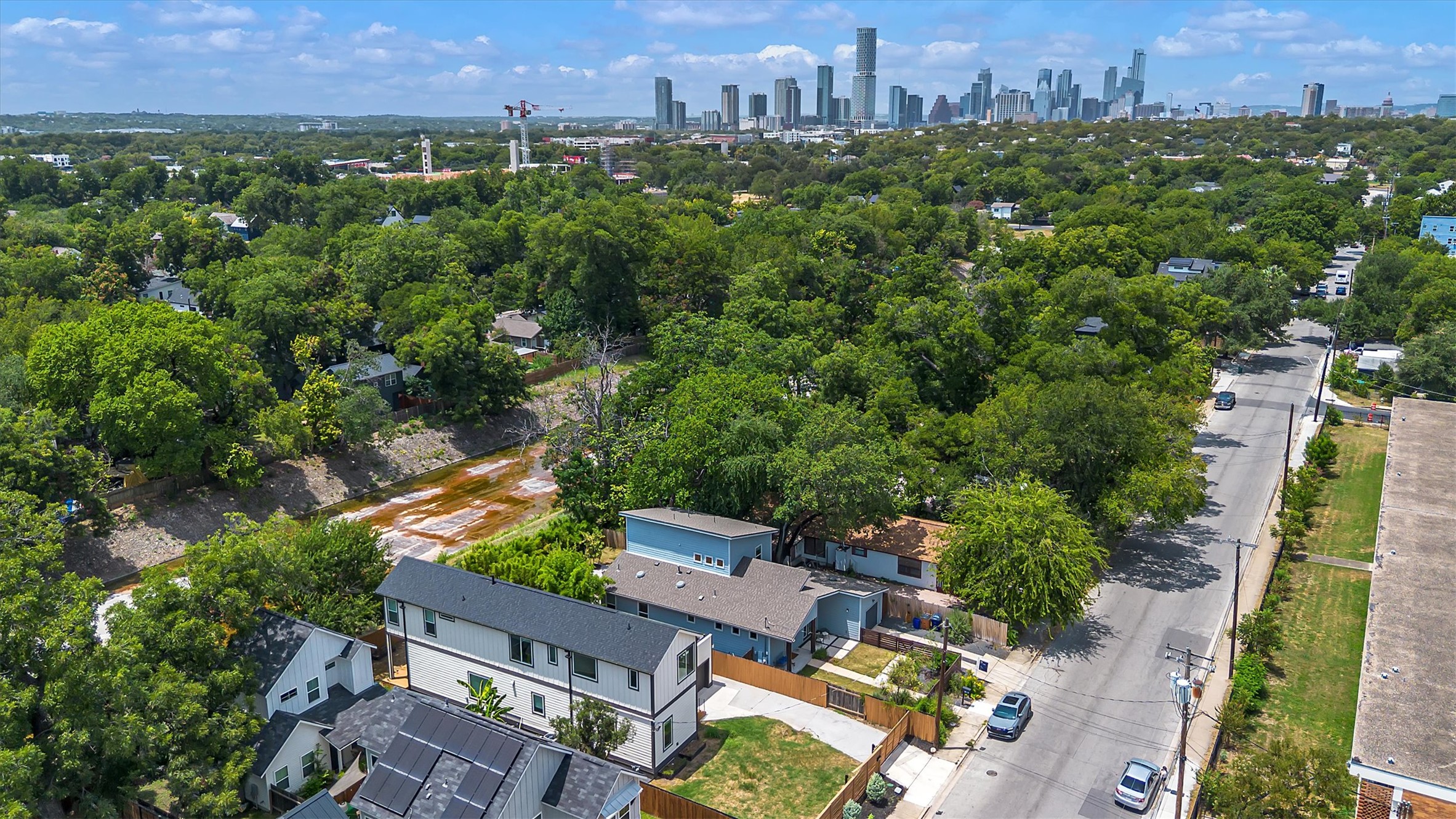 3101 Lyons Road Austin, TX 78702 - Photo 35 of 40 An aerial panorama showcases a verdant neighborhood with a vibrant city skyline on the horizon.