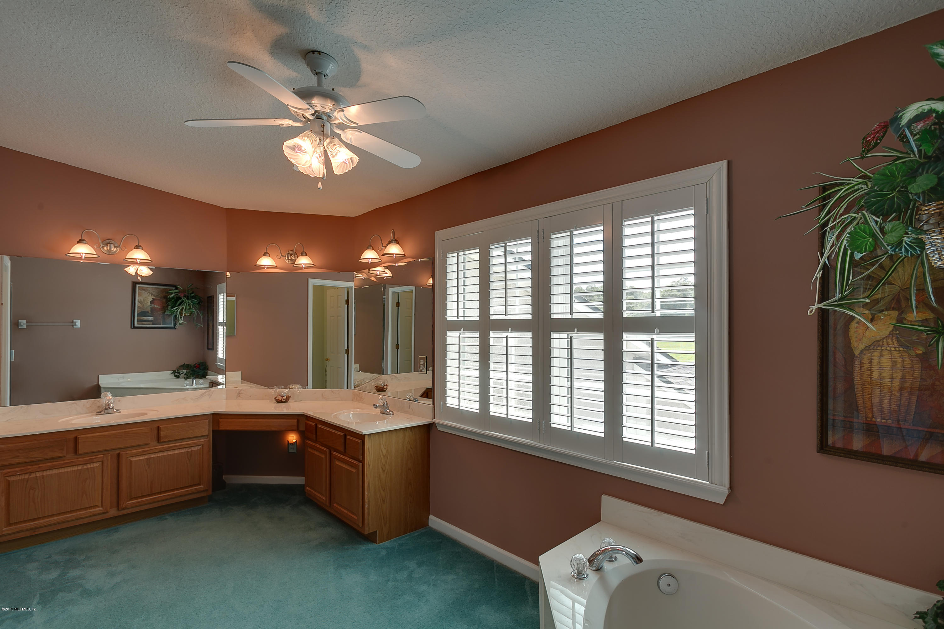 3105 Ravines Road Middleburg, FL 32068 - Photo 22 of 32 a bathroom with a double vanity sink a large mirror and a bathtub