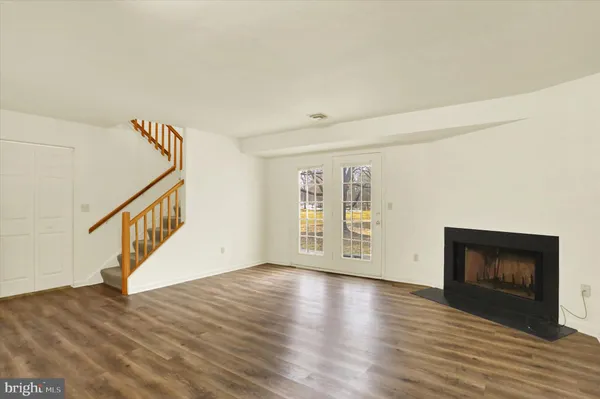 a view of an empty room with wooden floor fireplace and a window