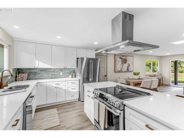 a kitchen with granite countertop a sink stainless steel appliances and white cabinets