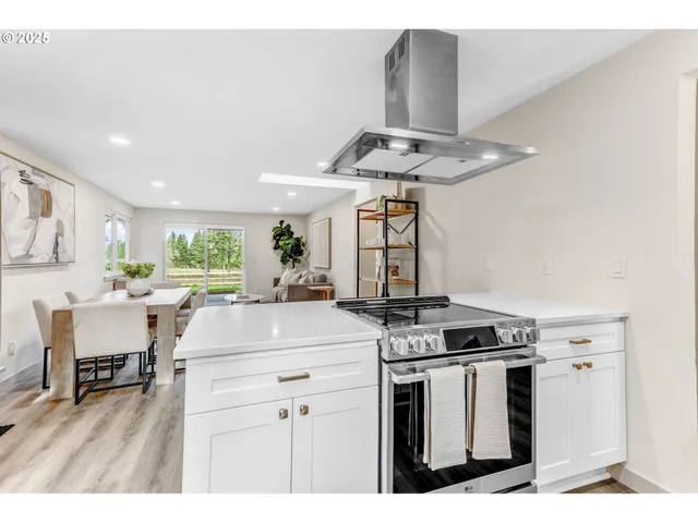 a kitchen with stainless steel appliances kitchen island a white stove a table and chairs