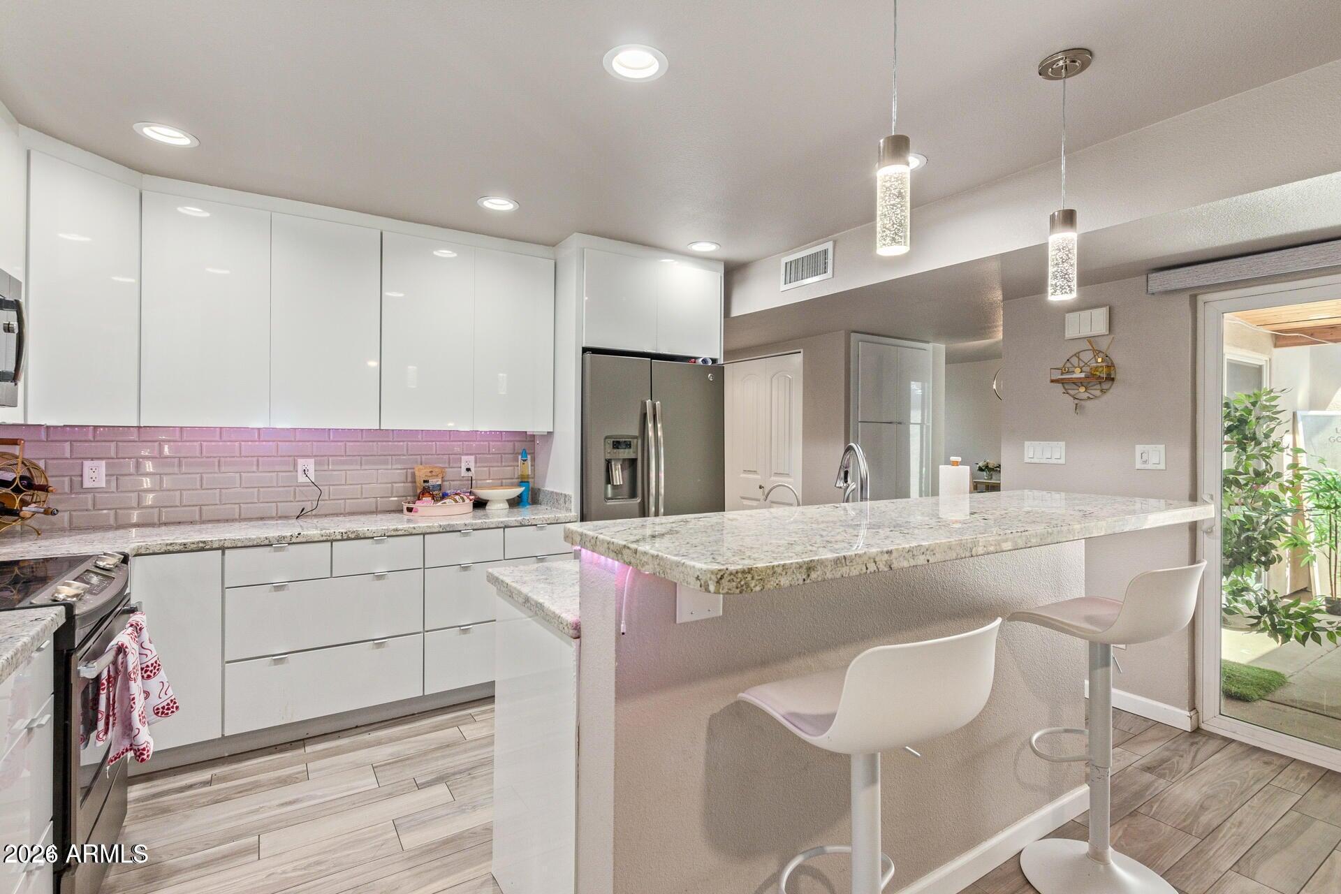 5913 East Thomas Road Scottsdale, AZ 85251 - Photo 1 of 26 a kitchen with granite countertop kitchen island a sink white cabinets and stainless steel appliances