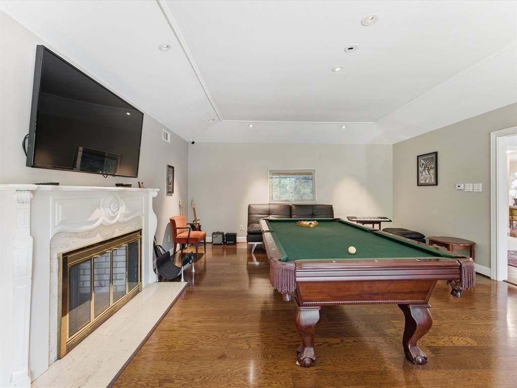 6160 Spring Valley Road Dallas, TX 75240 - Photo 6 of 40 Spacious entertainment area featuring rich wood-finish flooring, a decorative fireplace with a substantial hearth, recessed ceiling lighting, and a large window providing ambient light