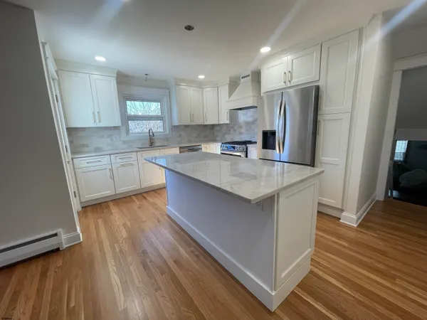 a kitchen with stainless steel appliances a refrigerator a sink dishwasher and a stove with wooden floor