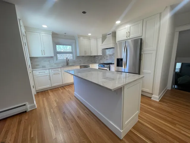 a kitchen with stainless steel appliances a refrigerator a sink dishwasher and a stove with wooden floor