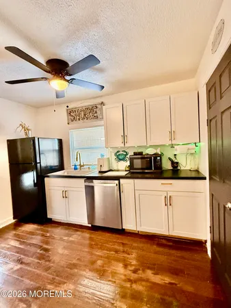 a view of a kitchen with stainless steel appliances granite countertop a refrigerator a stove a sink and dishwasher with wooden floor
