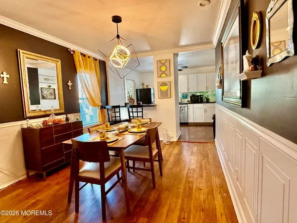 a dining room with wooden floor a chandelier a wooden table and chairs