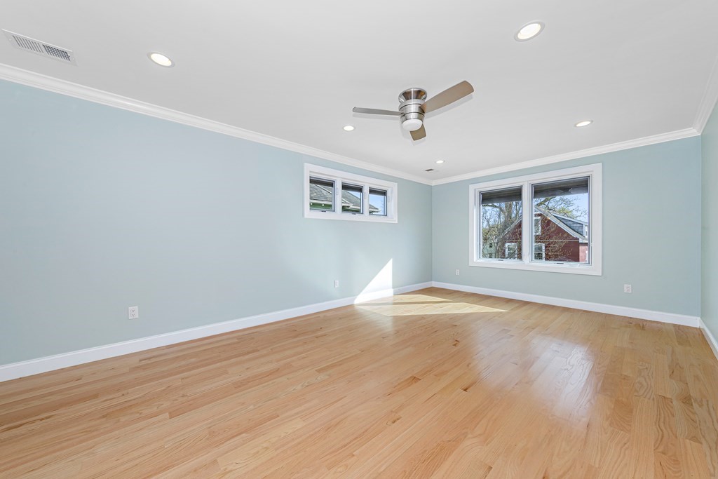31 Knoll Street Boston, MA 02131 - Photo 21 of 34 an empty room with wooden floor ceiling fan and windows