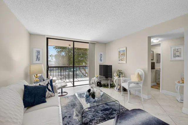 a living room with furniture a flat screen tv and a floor to ceiling window
