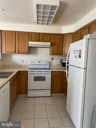 a kitchen with a white stove refrigerator and cabinets