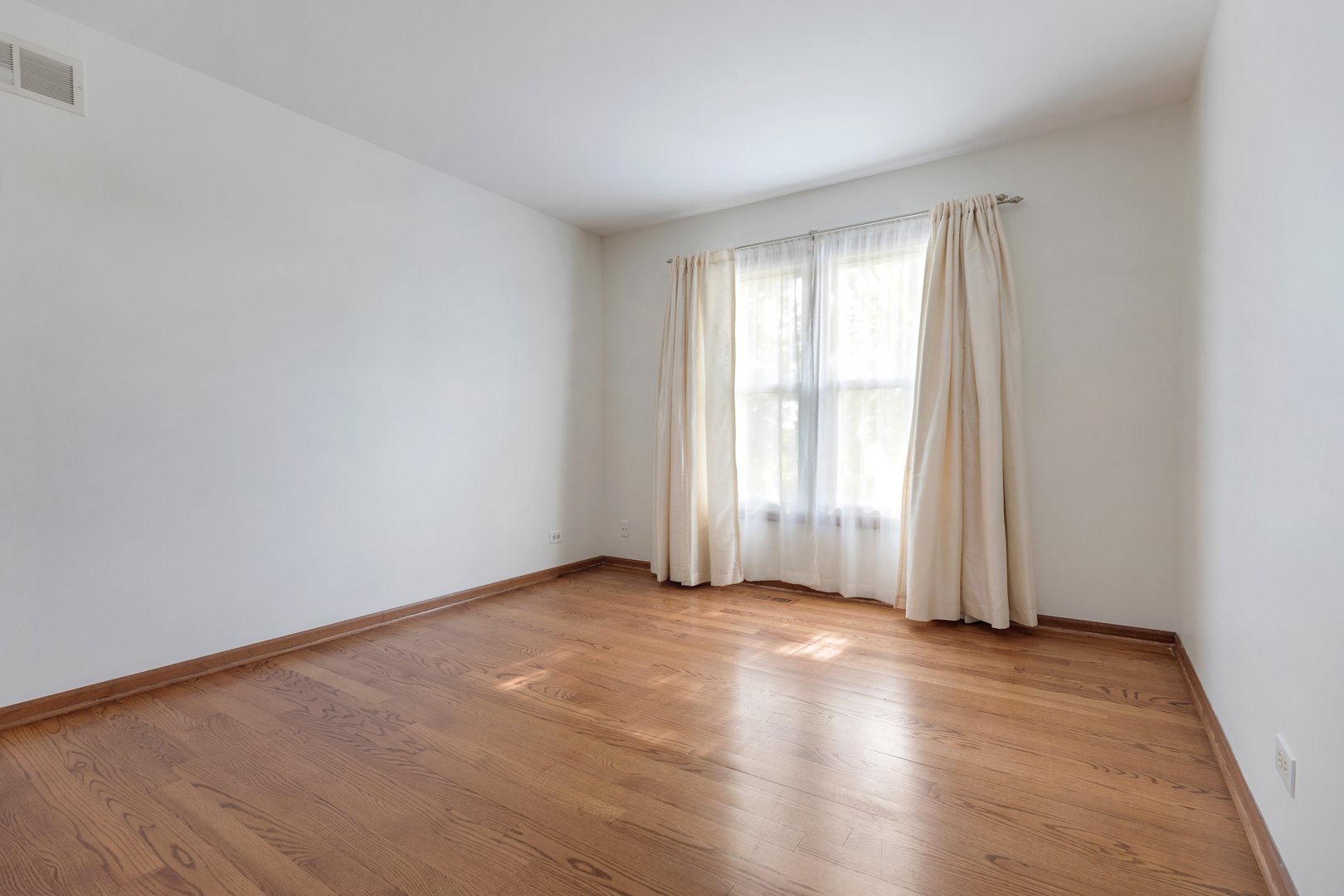 775 Harmon Boulevard Hoffman Estates, IL 60169 - Photo 12 of 27 an empty room with wooden floor and windows with curtains