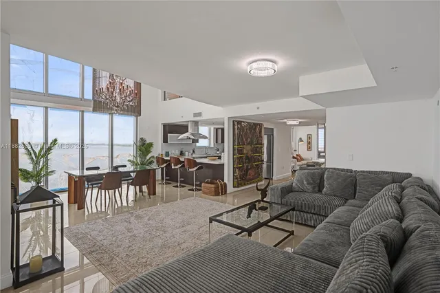 a living room with furniture kitchen view and large windows