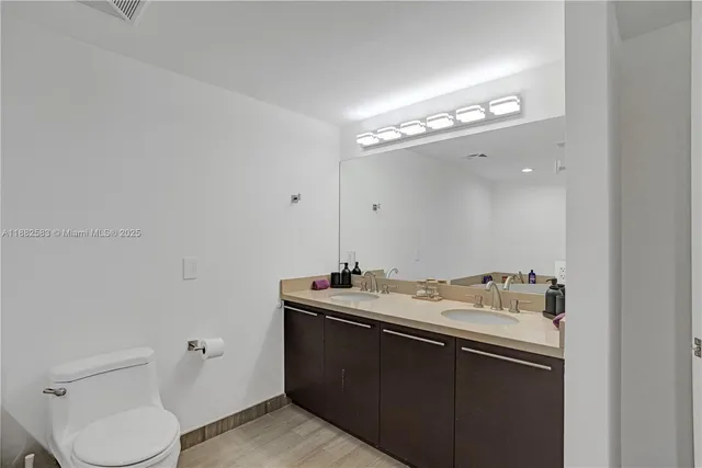 a bathroom with a sink vanity mirror and toilet