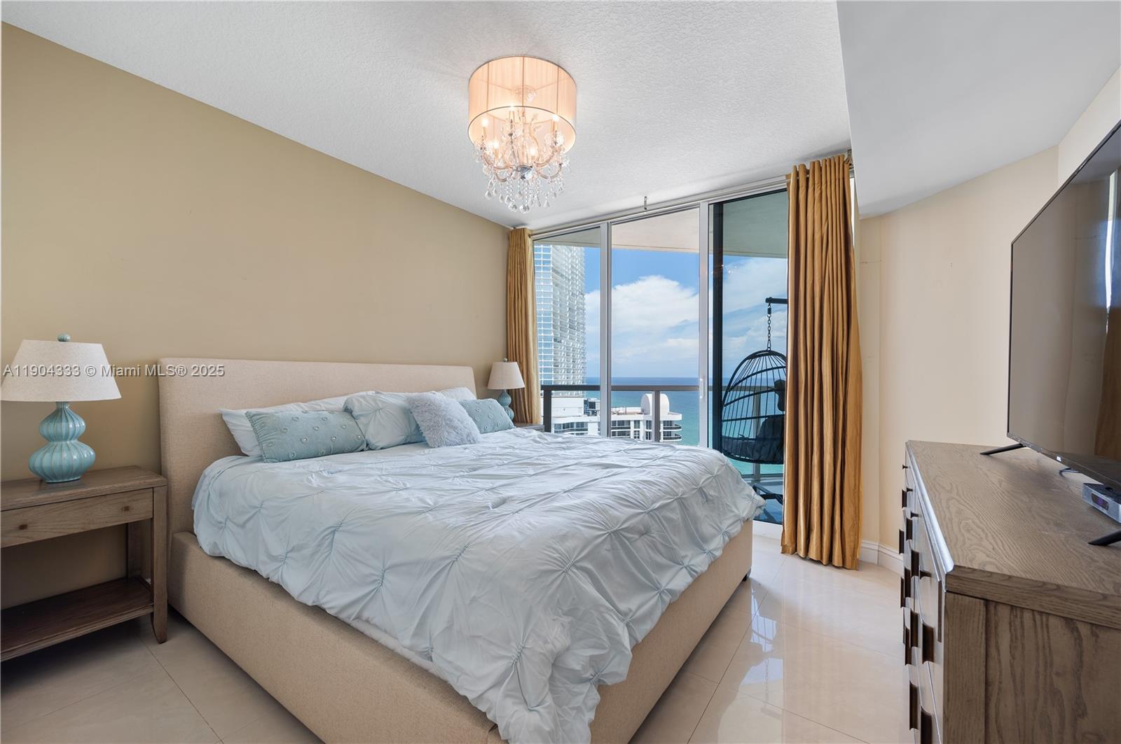 16699 Collins Avenue, Unit 3305 Sunny Isles Beach, FL 33160 - Photo 11 of 20 a bedroom with a bed and a chandelier