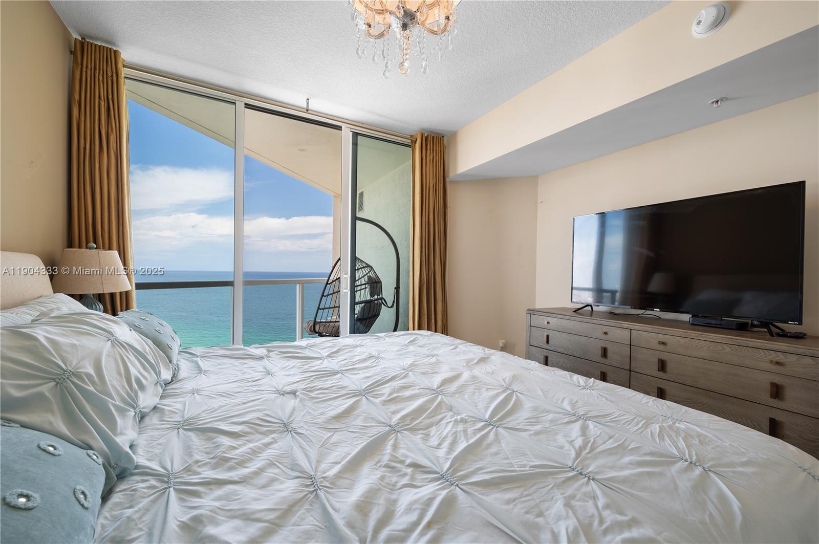 16699 Collins Avenue, Unit 3305 Sunny Isles Beach, FL 33160 - Photo 12 of 20 a bedroom with a large bed and a flat screen tv