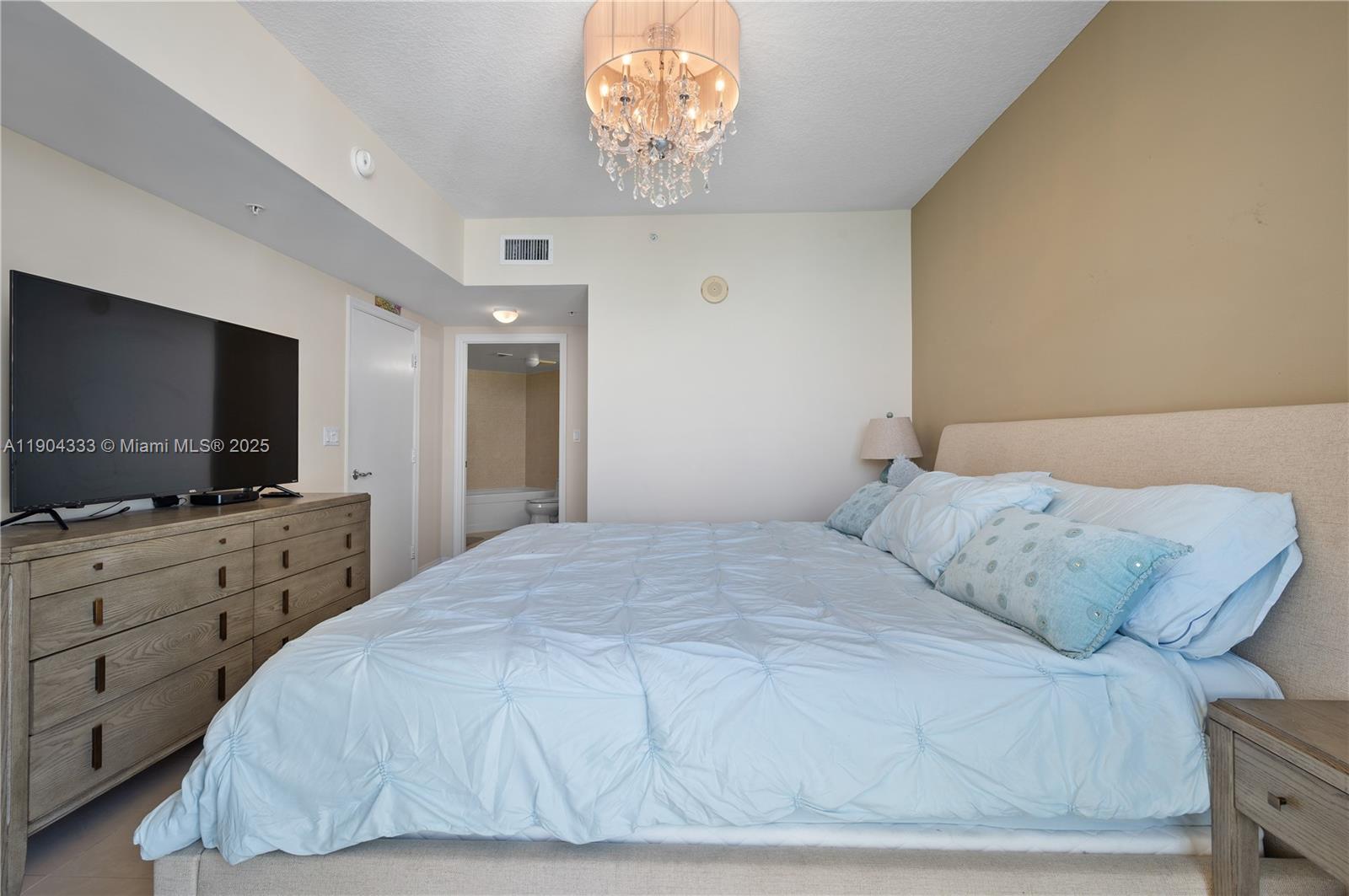 16699 Collins Avenue, Unit 3305 Sunny Isles Beach, FL 33160 - Photo 13 of 20 a bedroom with a bed and a flat screen tv