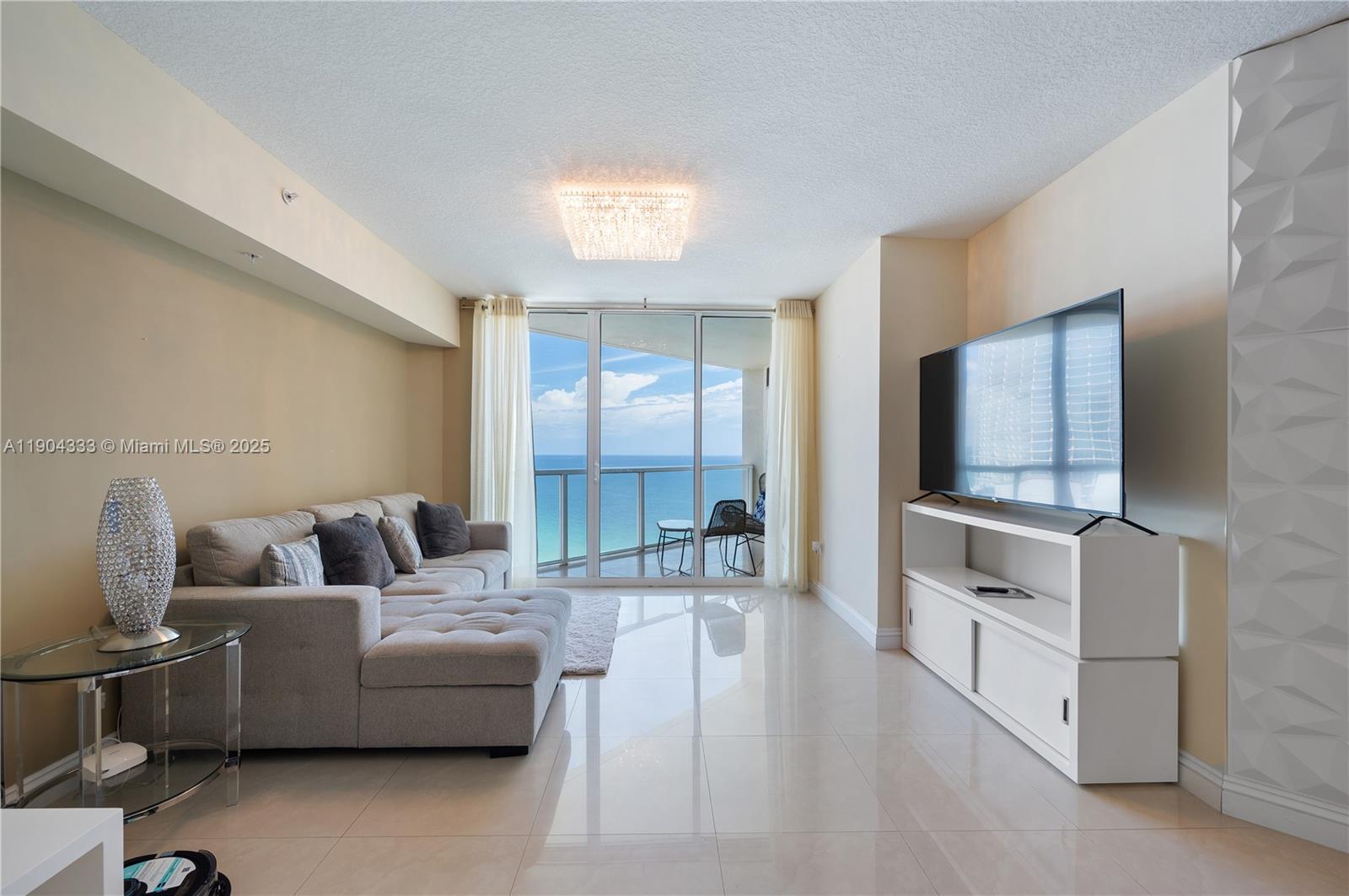 16699 Collins Avenue, Unit 3305 Sunny Isles Beach, FL 33160 - Photo 5 of 20 a living room with furniture and a flat screen tv
