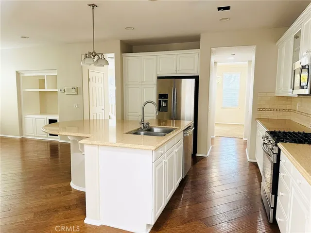 a kitchen with a refrigerator a sink and wooden floor