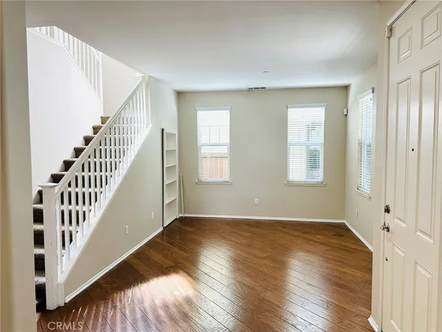 a view of an empty room with wooden floor and stairs